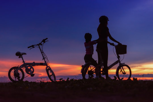 Silhouettes of biker family on the beach at beautiful sunset.	