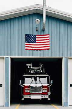 Fire truck parked in firehouse with American flag