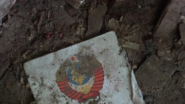 Chernobyl, Ukraine - 17th of June 2017: Visit to Zalesye village in Chernobyl zone - 4K USSR emblem on a page of old book found in abandoned village house