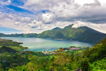 Fototapeta na wymiar Panoramic view of a lake surrounded by mountain, tropical landscape with colorful clouds in the sky. Fisheries and settlements on the shore. Danau Batur, Gunung Batur, Kintamani, Bali, Indonesia.