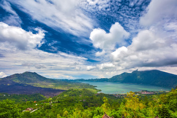 Panoramic view of a lake surrounded by volcanic mountains, tropical landscape with colorful clouds in the sky. Danau Batur, Gunung Batur, Kintamani, Bali, Indonesia.