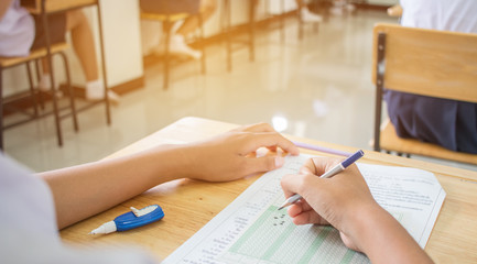 Uniform School Asian students taking exams writing answer optical form with pencil in high school classroom, view of having exams in class on seat rows, Education test and literacy concept. © smolaw11