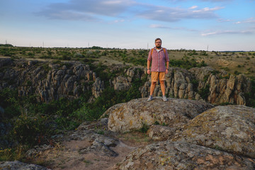 stylish young man with beard standing on the precipice of the canyon