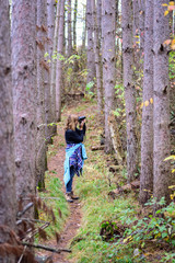 Naklejka na ściany i meble woman taking photos in pine forest