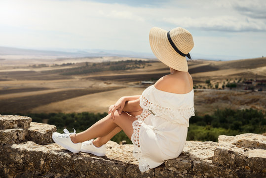 A girl in a white dress is looking at a meadow. Travel, rest, vacation. Tunisia.
