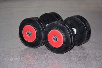 Pair of black and red dumbbells isolated on a grey background.