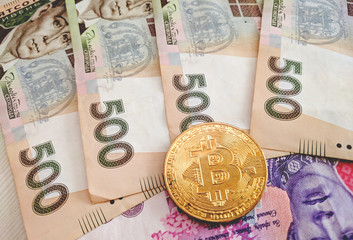 Golden Bitcoin coin on a hryvnia close up
