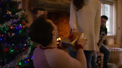  Happy adult family together at Christmas, exchanging gifts by the fire