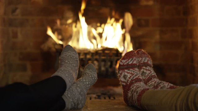  Close up feet of couple in cosy socks warming their toes by the fire