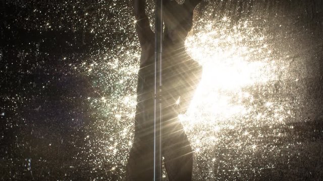 amazing pole dancer showing her skills against sparkling gold background