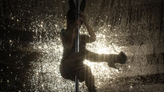 amazing pole dancer showing her skills against sparkling gold background