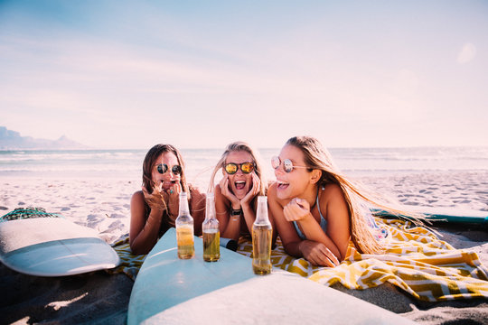 Young adult girls drinking beer at the beach and having fun
