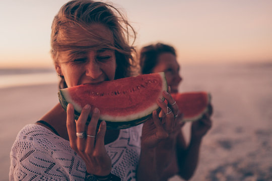 Woman eating watermelon at the beach in sunset