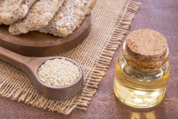 Sesame oil in glass jar and sesame seeds on wooden spoon - Sesamum indicum