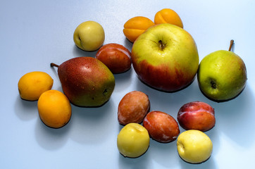 Summer fruits: apples, pears, apricots, plums on a blue table