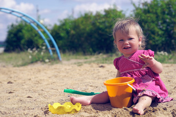 Adorable baby play with sand in sandbox on playground on a hot summer day.
