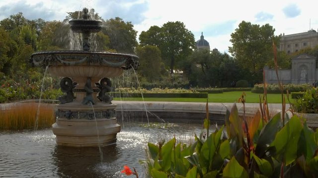 Camera rises past plants to reveal beautiful fountain in Volksgarten Vienna. Taken on a sunny September morning