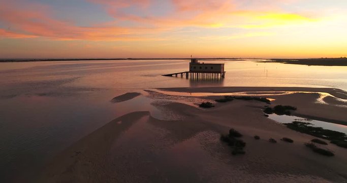 Aerial sunset and historic life-guard building at Fuseta fishing town, in Ria Formosa wetlands nature conservation park, Algarve. Portugal