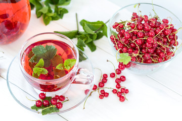 Redcurrant drink in transparent glass carafe and cup
