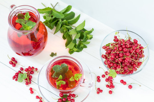 Redcurrant drink in transparent glass carafe and cup