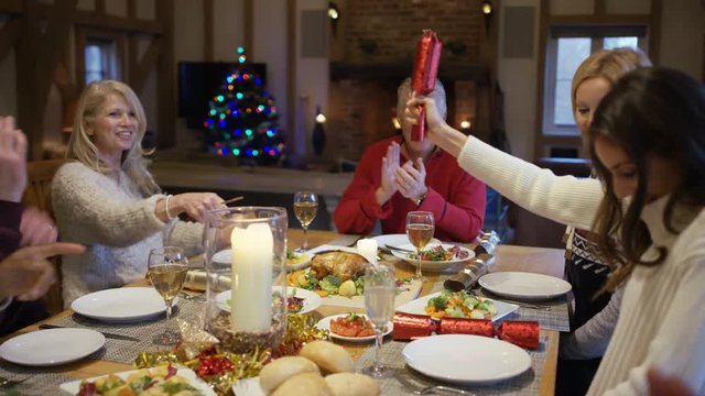 Happy family together at Christmas, pulling crackers at the dinner table