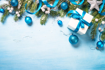 Christmas background on blue. Present gift box, branch, balls and decorations top view.