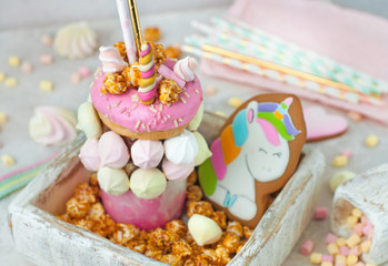 Freak shake decorated as unicorn in the wooden box filled with popcorn