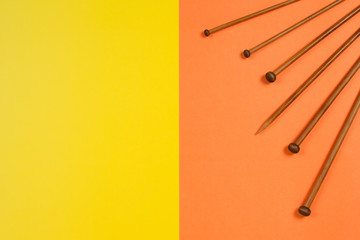 Variety of bamboo knitting needles in different sizes on yellow and orange background