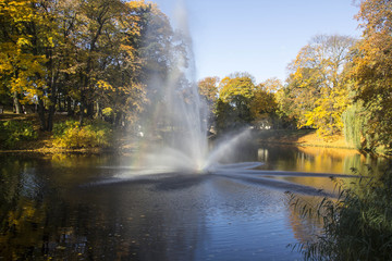 Fountain and rainbow in Riga Canal that flows through Bastion park autumn background with colored leaves (Bastejkalns). Latvia autumn 