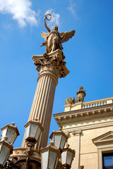 Obraz premium Statue of an angel on a pillar / Neo-Renaissance sculpture towering high on a column