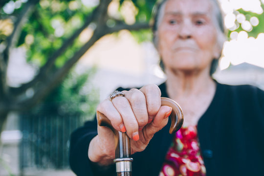Senior woman portrait with her cane - detail of her hand holding the cane