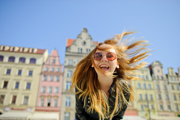 Cheerful young girl in sunglasses against the backdrop of a beautiful old building.