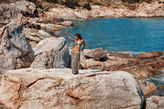 tribal woman belly dancer dancing on stone beach