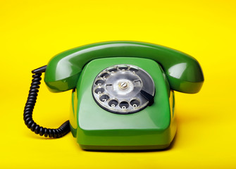 Old green telephone on a yellow background