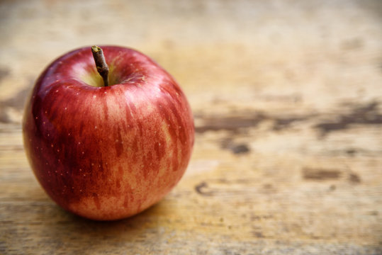 Red apple on rustic wooden background. Autumn fruit