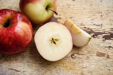 Bio apples with slice on rustic wooden background. Autumn fruits