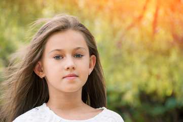 Fototapeta premium Beautiful little girl in the park, with long hair and and a sweet, gentle look. Happy childhood concept.