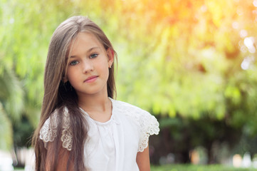 Beautiful little girl in the park, with long hair and and a sweet, gentle look.  Happy childhood concept.