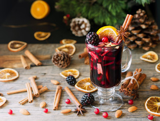 glass of hot mulled wine for the new year with ingredients for cooking, nuts and Christmas...