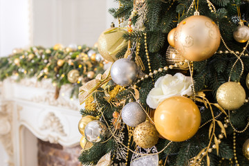 Christmas tree with golden christmas balls near decoreted fireplace.