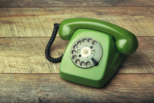 Old green telephone on a wooden background