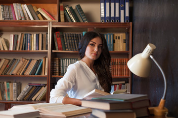 girl sitting at the table reading a book is preparing for the exam