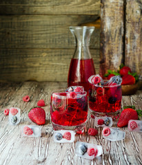 Summer berry lemonade with frozen berries on a wooden rustic table, selective focus