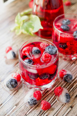 Summer berry lemonade with frozen berries on a wooden rustic table, selective focus
