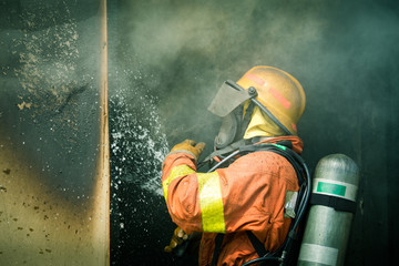 Obraz premium a firefighter water spray by high pressure nozzle to fire surround by smoke copy space