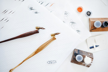 two pen for writing ink on a background of a table with paper and a stencil for learning the perfect handwriting.