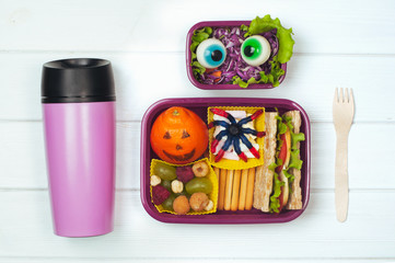 Obraz premium Halloween lunch box near thermo mug on white wooden background