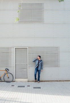 Young man in front of a metal building talking on phone