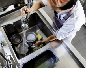 Top view of kitchen staff washing utensils at sink - obrazy, fototapety, plakaty