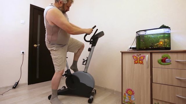 man engaged on exercise bike in room